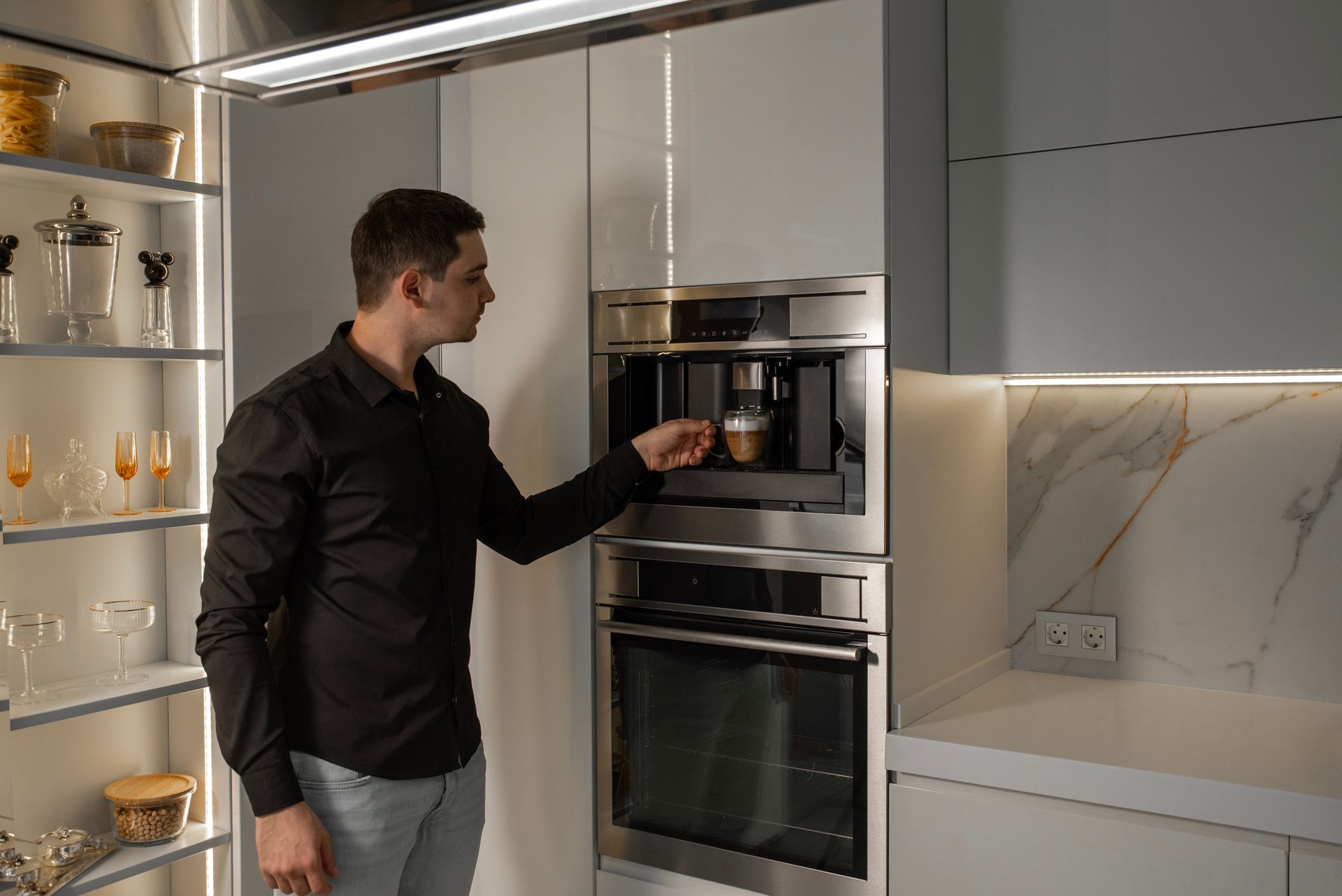 Deux ouvriers installent des meubles de cuisine dans une cuisine lumineuse, l'un sur une échelle et l'autre accroupi avec des outils.
