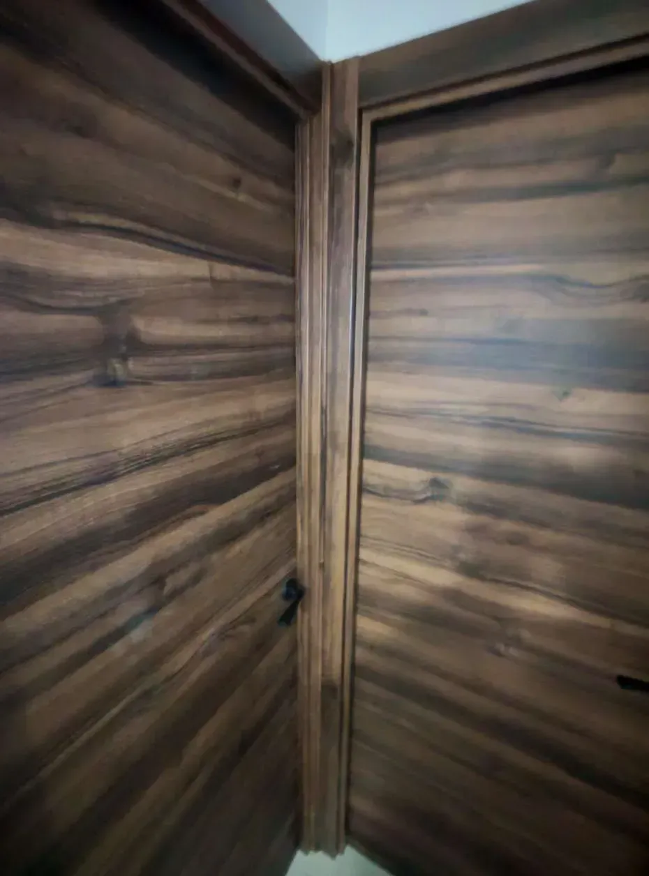 Esquina interior revestida de madera, con molduras verticales y paredes de vetas de madera oscura.