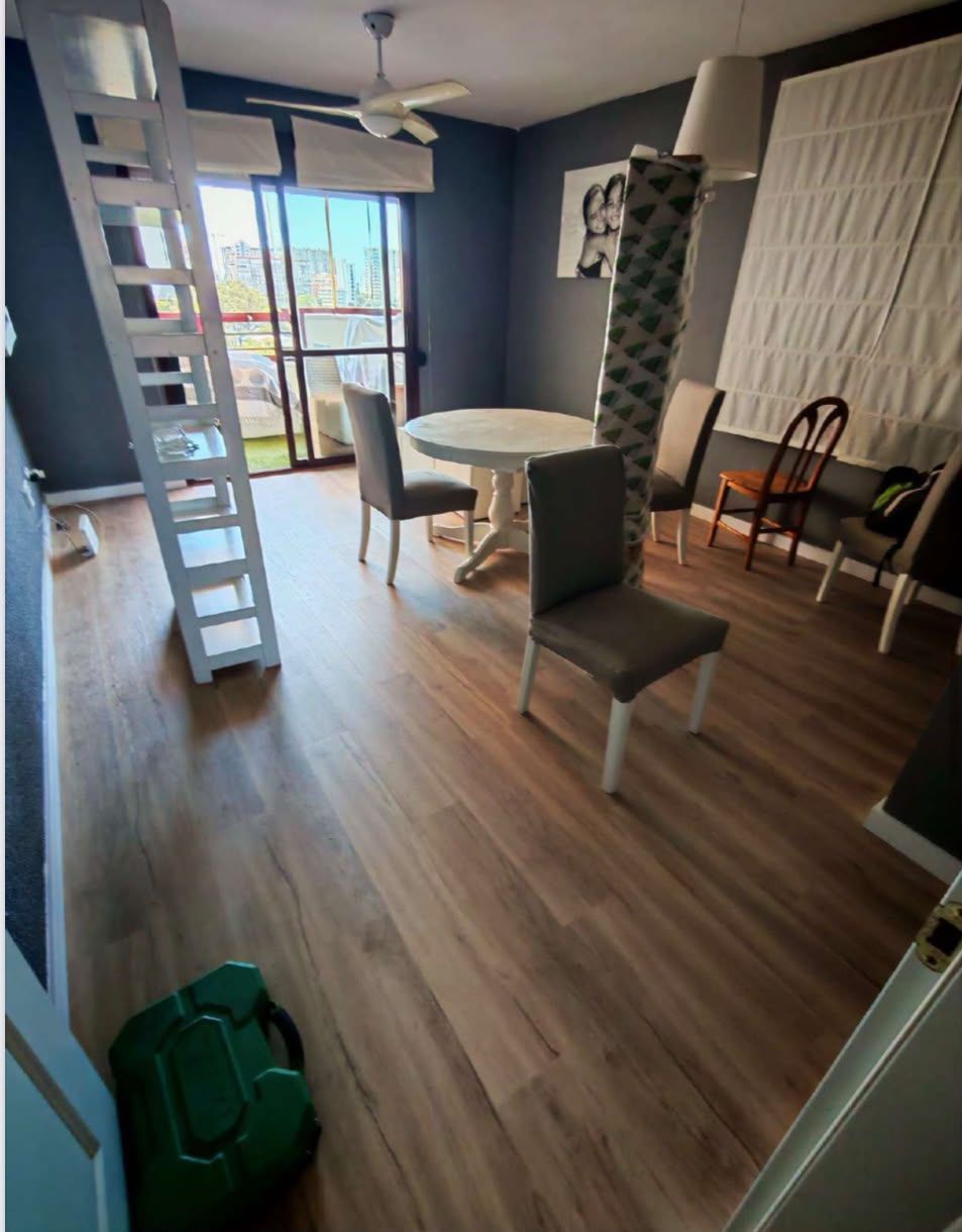 Comedor moderno con mesa, sillas, suelo de madera y un gran ventanal con vistas a la ciudad