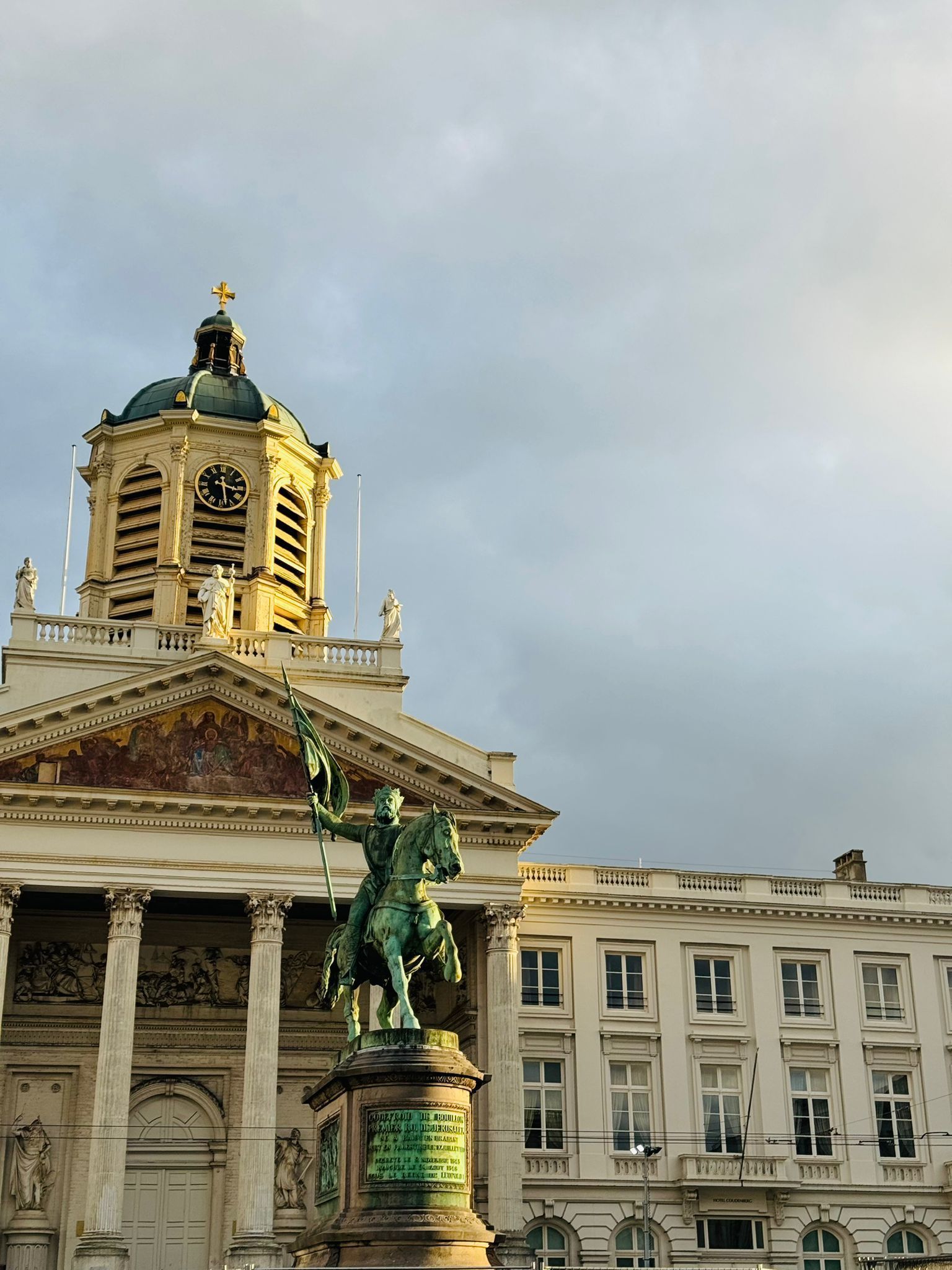 Un grand bâtiment avec une tour d'horloge et une statue d'un homme sur un cheval