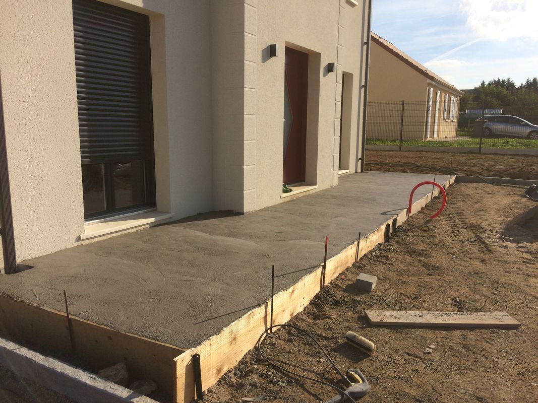 Création d'une terrasse devant une maison, avec coffrage, coulage de dalle et préparation des aménagements extérieurs.