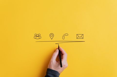 Main dessine une ligne sous des icônes représentant les contacts, la localisation, le téléphone et l’e-mail sur fond jaune.