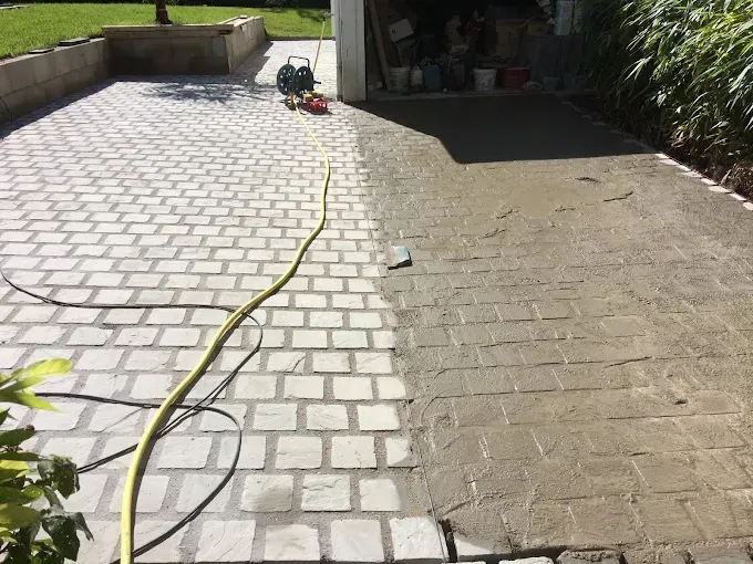 Nettoyage d'une allée en pavés autobloquants devant un garage.