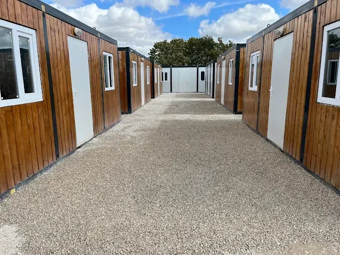 Une rangée de petites cabanes en bois borde une allée de gravier.