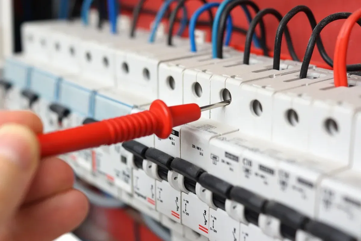 Eine Person testet mit einem Multimeter einen Leistungsschalter.