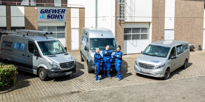 Eine Gruppe von Menschen steht vor drei Lieferwagen.