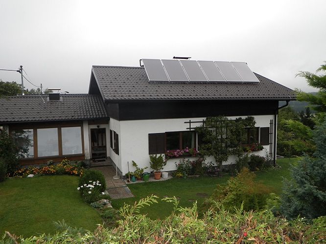 Ein weißes Haus mit Solarzellen auf dem Dach