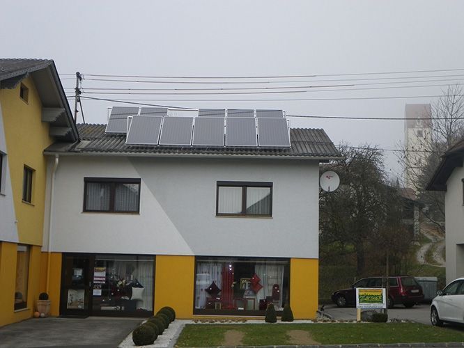 Ein gelb-weißes Gebäude mit Solarmodulen auf dem Dach