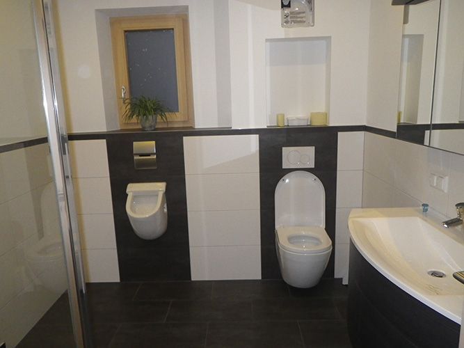 Ein Badezimmer mit zwei Toiletten und einem Urinal