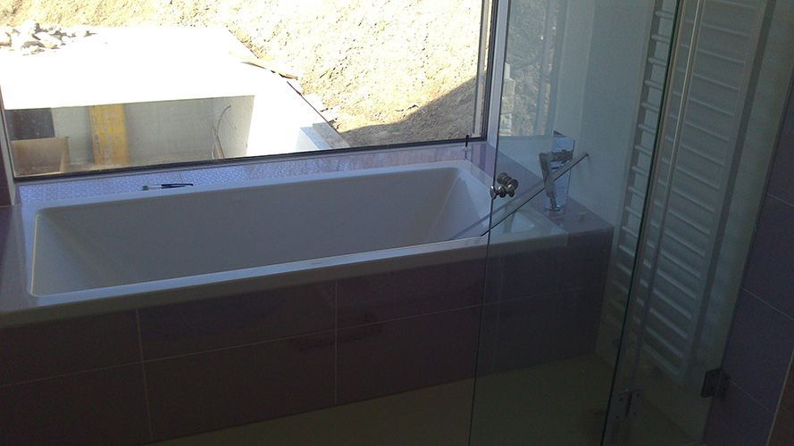 Eine Badewanne in einem Badezimmer neben einem Fenster.