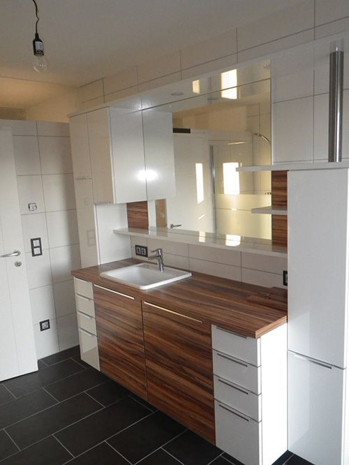 Ein Badezimmer mit weißen Schränken und Holzarbeitsplatten