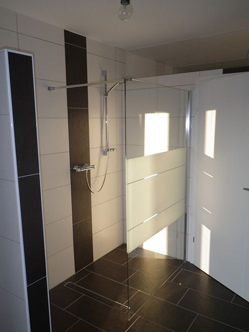 Ein Badezimmer mit schwarzen und weißen Fliesen und einer ebenerdigen Dusche