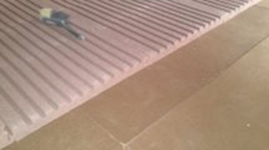 Auf einem gefliesten Boden liegt eine Matratze.