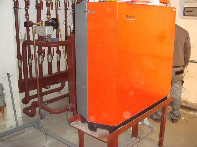 Auf einem Holztisch steht neben Rohren eine große orangefarbene Kiste.