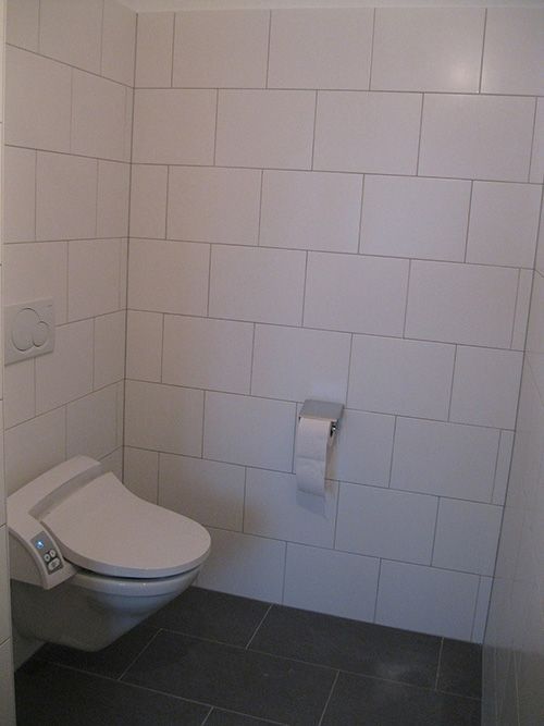 Ein Badezimmer mit weißen Fliesen und einer Toilette