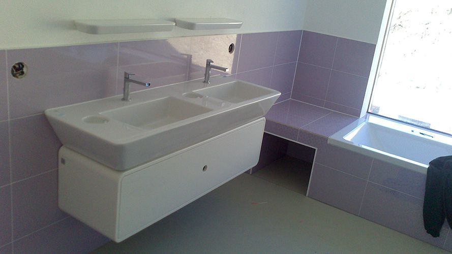 Ein Badezimmer mit lila Fliesen und zwei Waschbecken