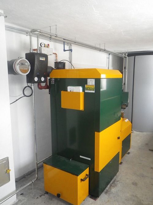 Ein grün-gelber Heizkessel steht in einem Raum