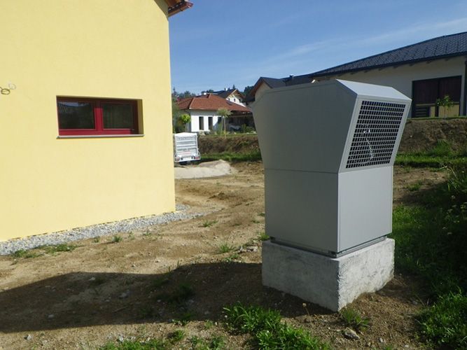 Ein gelbes Gebäude mit einem grauen Kasten davor