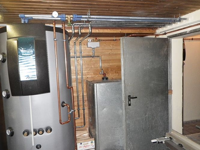 Ein Raum mit einer Heizung und von der Decke hängenden Rohren