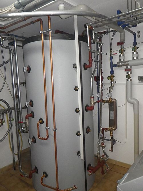 Ein großer weißer Tank, umgeben von Kupferrohren