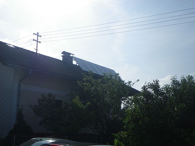 Ein Auto ist vor einem Haus mit einem Solarpanel auf dem Dach geparkt