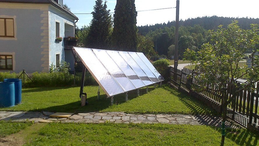 Eine Reihe von Solarmodulen liegt im Gras vor einem Haus