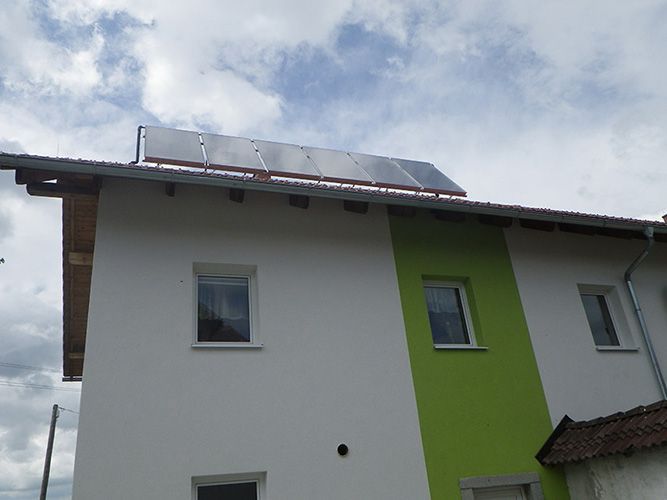 Ein weiß-grünes Haus mit Solarzellen auf dem Dach