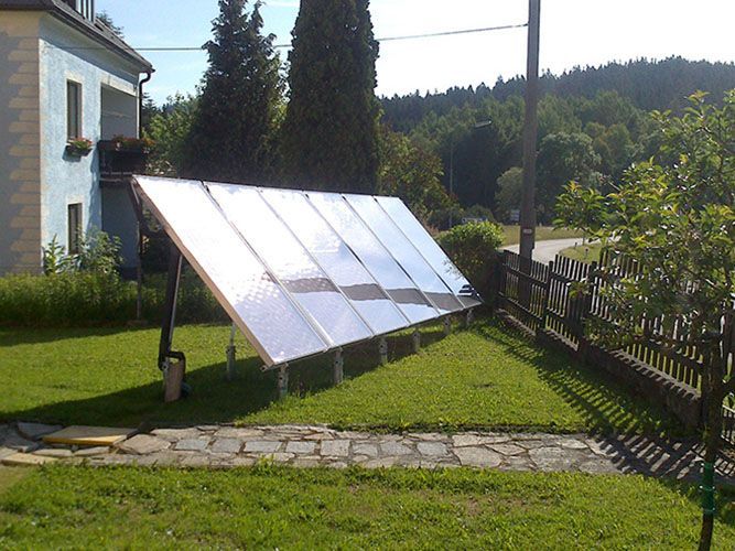 Eine Reihe von Solarmodulen liegt im Gras vor einem Haus