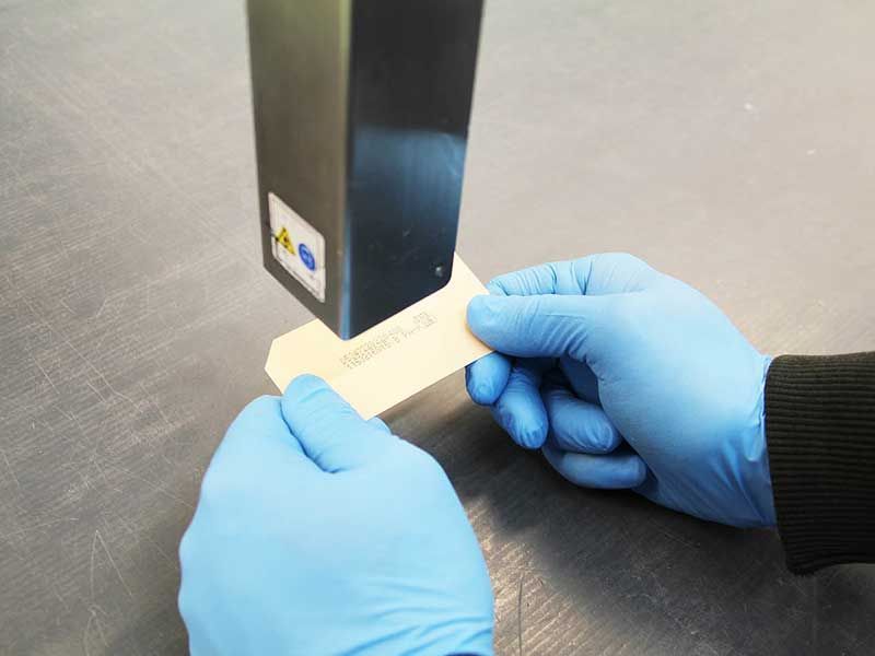 Hände in blauen Handschuhen halten ein Etikett