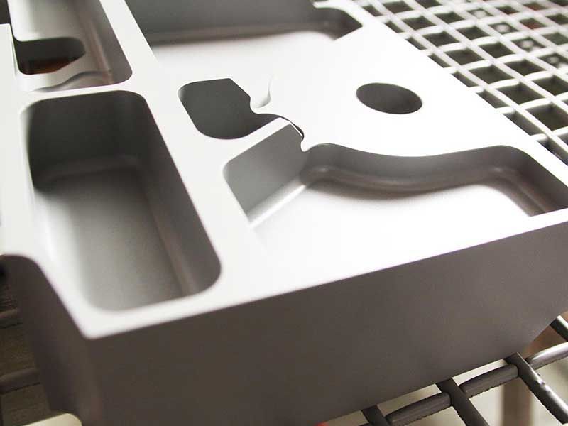 Bearbeitetes Aluminiumteil, grau, mit verschiedenen Aussparungen