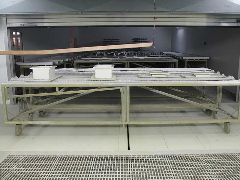 Holzbretter und Metallteile auf Rollgestellen in einem Industrieofen.