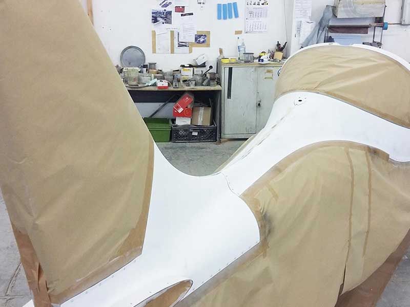 In einer Werkstatt wird an einem weißen und hellbraunen Objekt gearbeitet