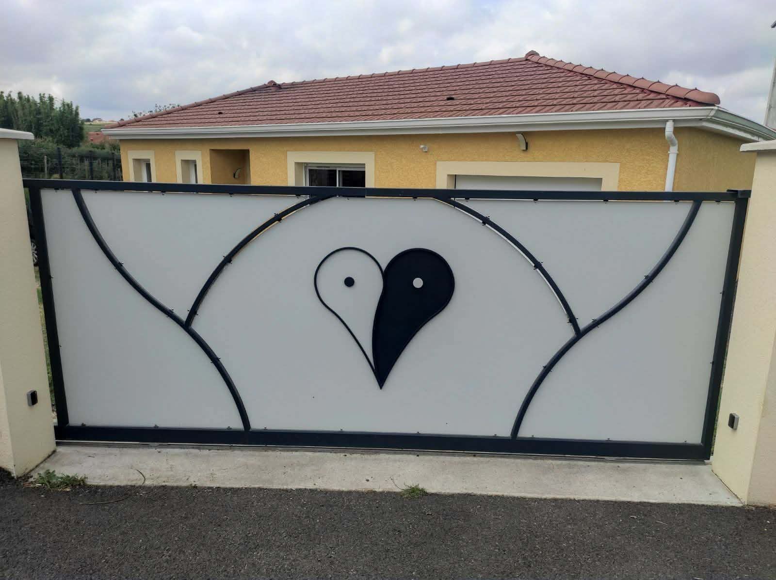 Un large portail d'allée en métal blanc orné d'un grand symbole yin-yang central en forme de cœur noir et blanc.