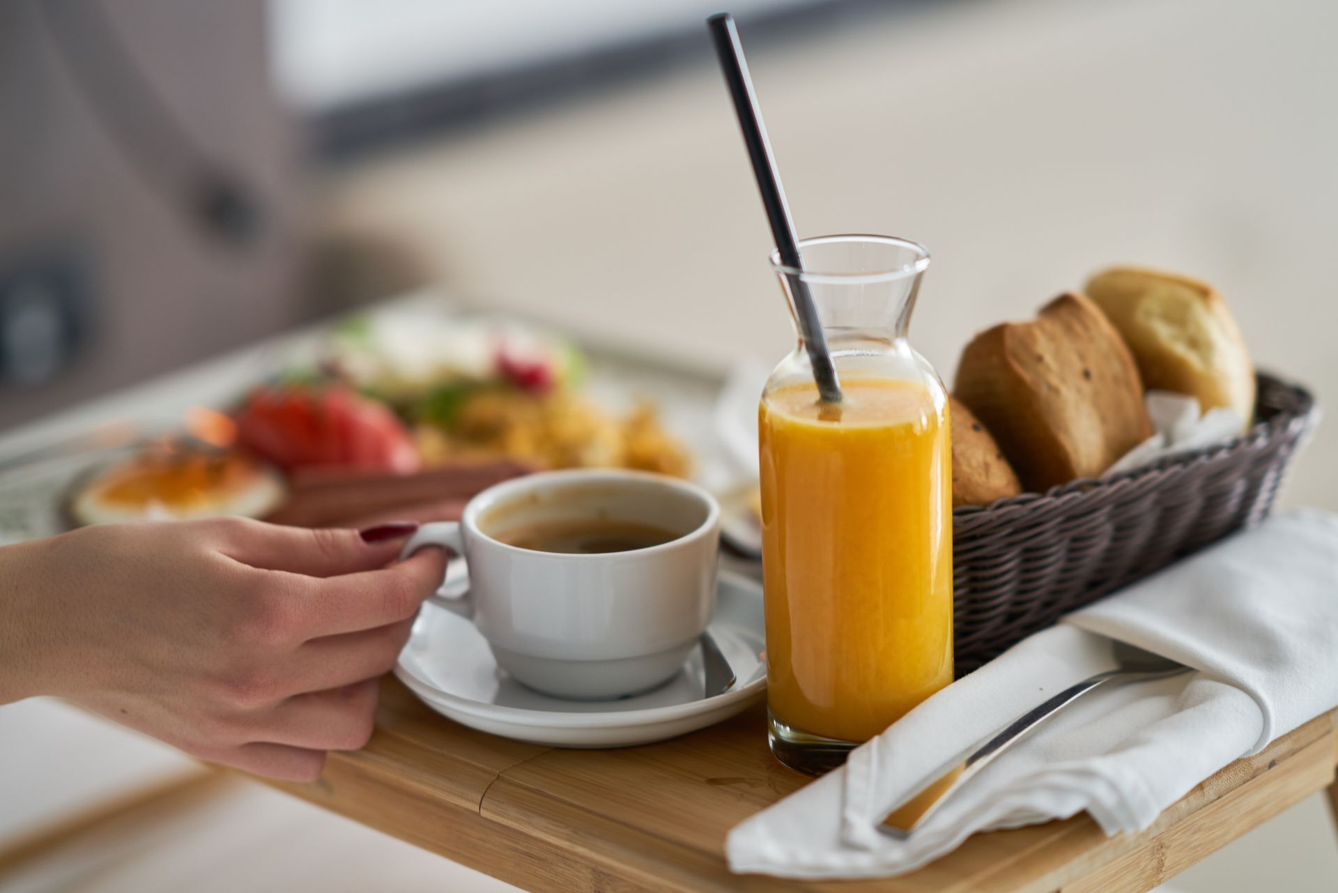 Main d'une femme attrapant une tasse sur un plateau de petit déjeuner