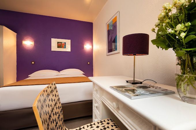 Chambre d'hôtel avec un lit deux places et un mur violet