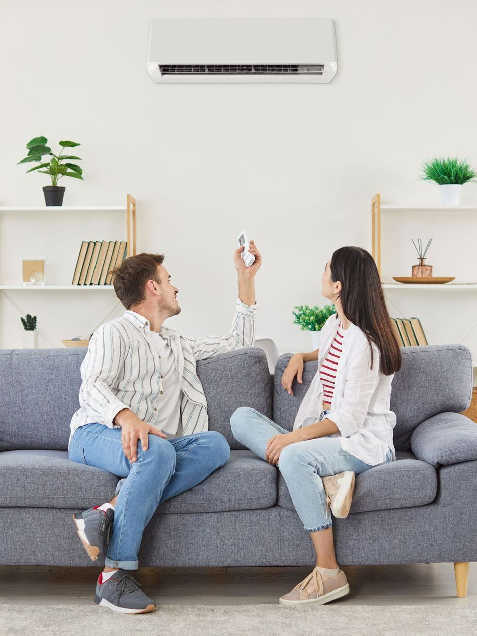 Couple assis sur un canapé allumant la climatisation