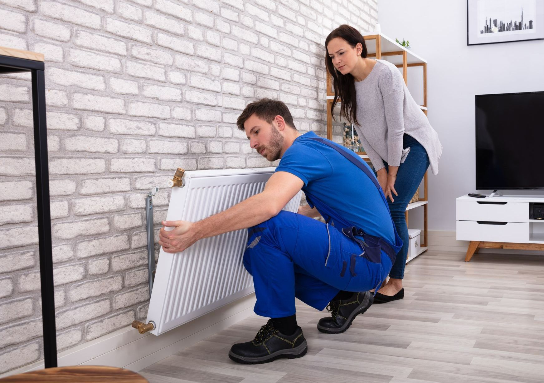 Un chauffagiste installe un radiateur