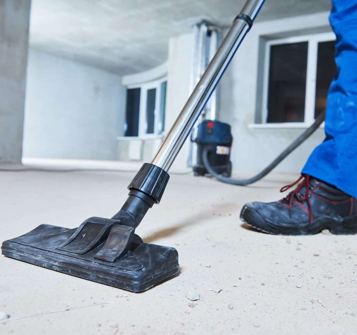 Una persona está usando una aspiradora en un piso de concreto.