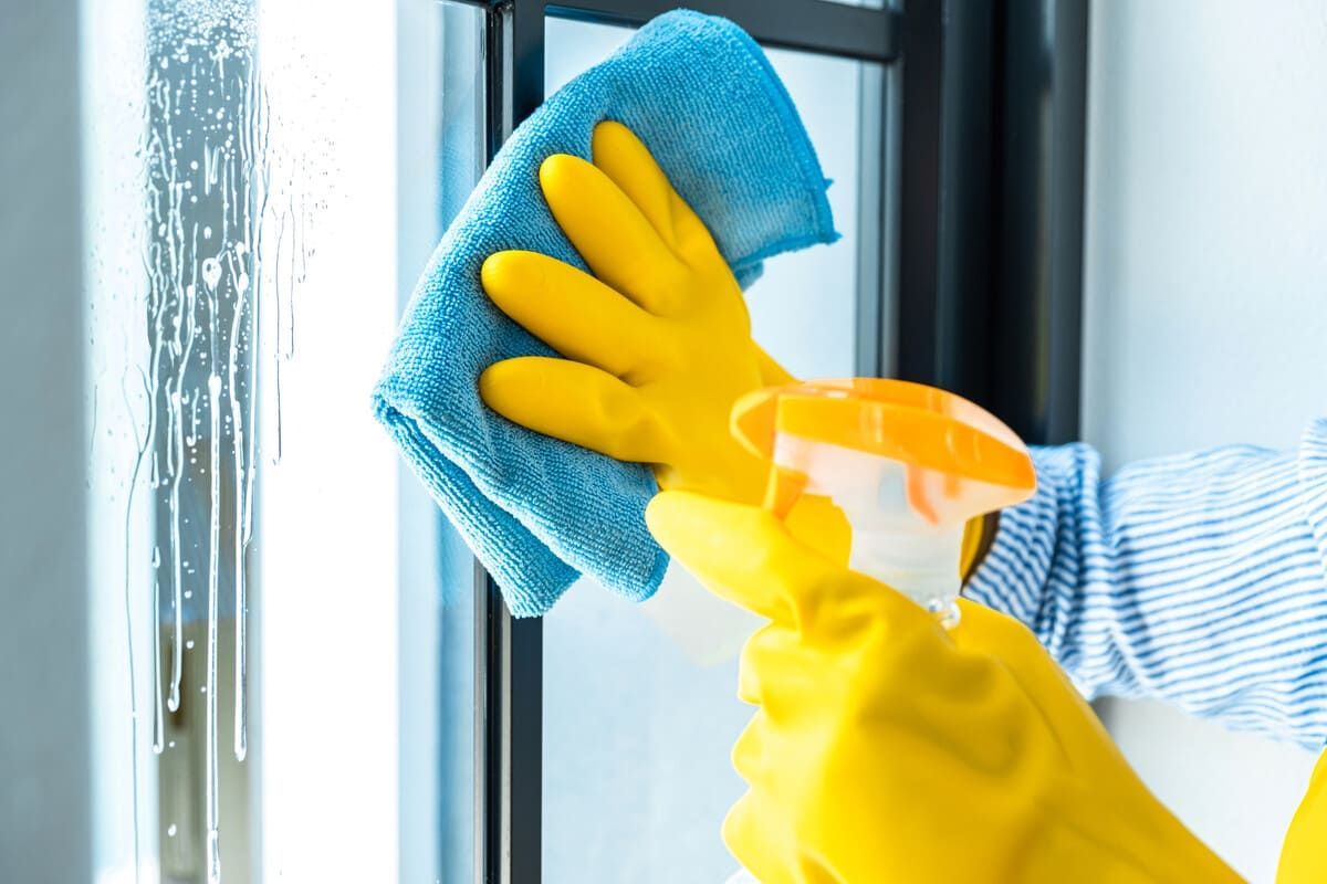 Una persona que lleva guantes amarillos está limpiando una ventana con un paño.