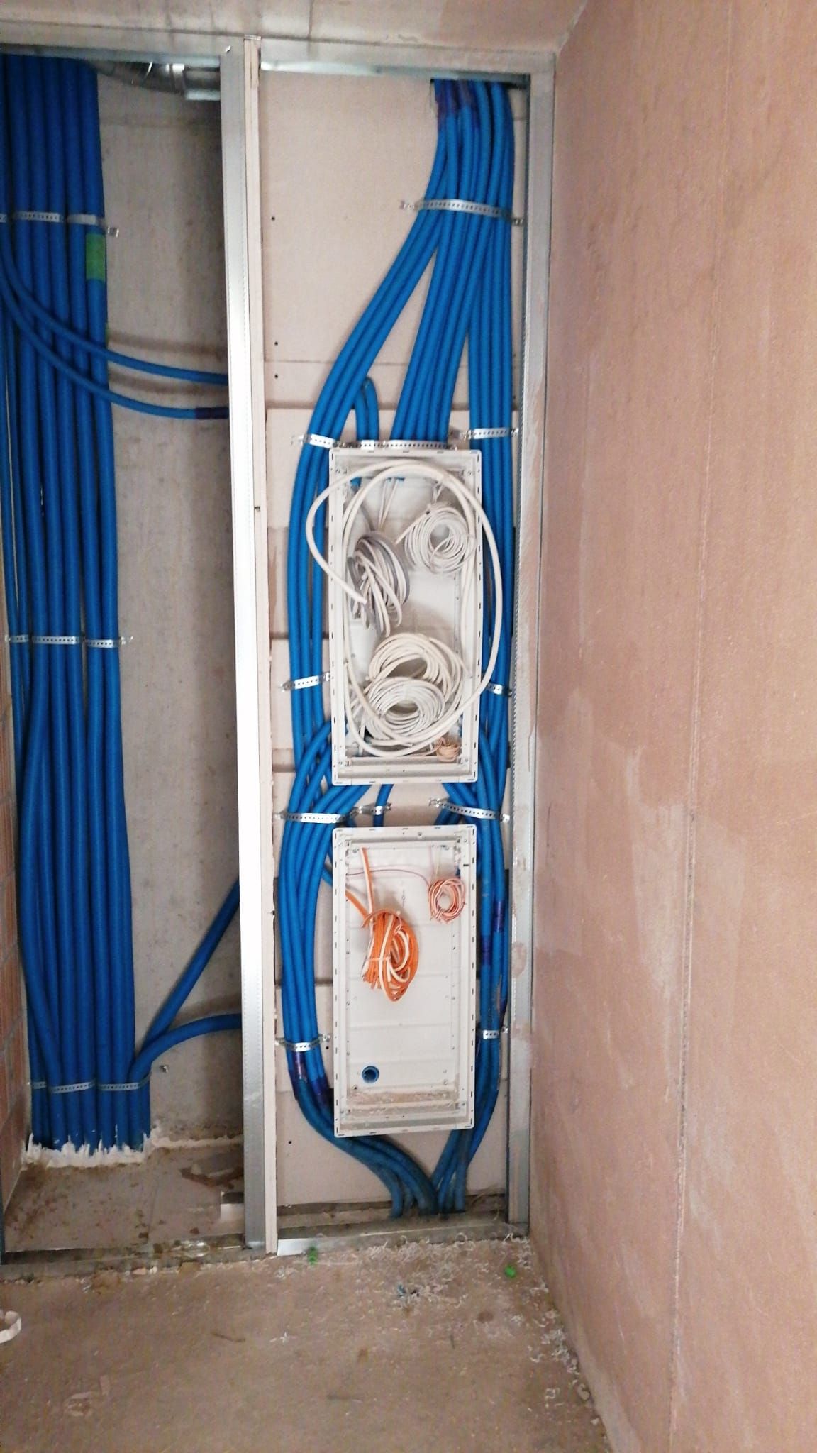 Elektrischer Verteilerkasten mit freiliegenden gelben und violetten Drähten, montiert an einer Ziegelwand im Inneren eines Gebäudes.