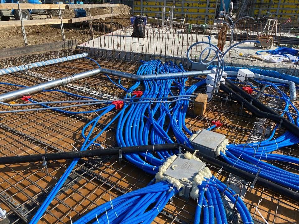 Baustelle mit blauen Elektrokabeln, die über einer Stahlbetonfundamentplatte gebündelt sind