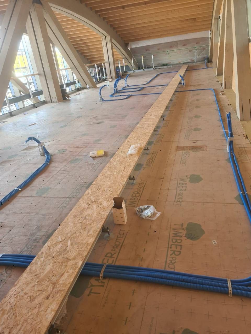 Im Bau befindlicher Dachboden in Holzrahmenbauweise mit OSB-Platten, blauen Kabeln und freiliegenden Dachsparren