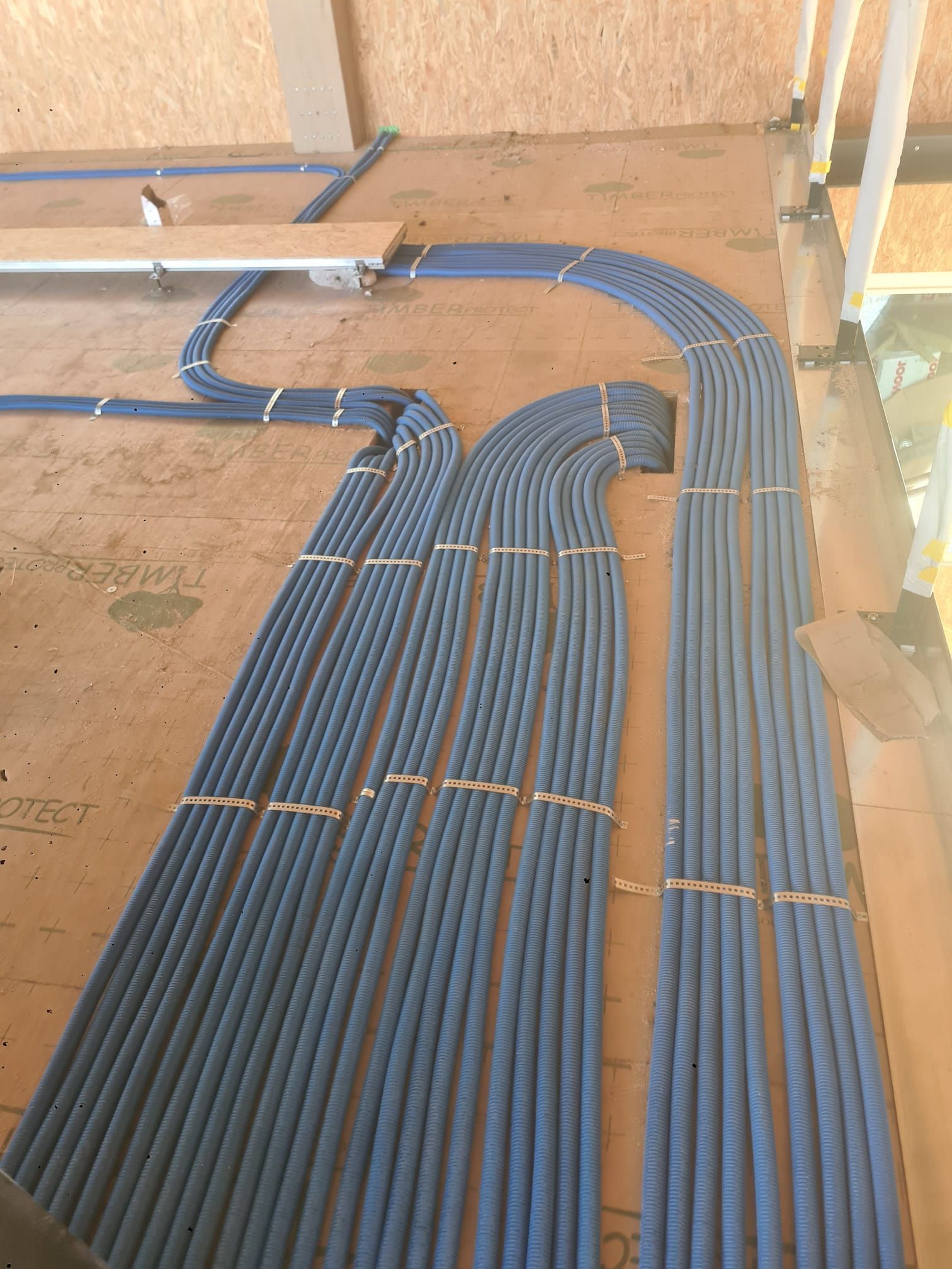 Innendecke mit freiliegenden silbernen Lüftungsrohren, abgehängten Paneelen und einer Leiter in einem im Bau befindlichen Raum
