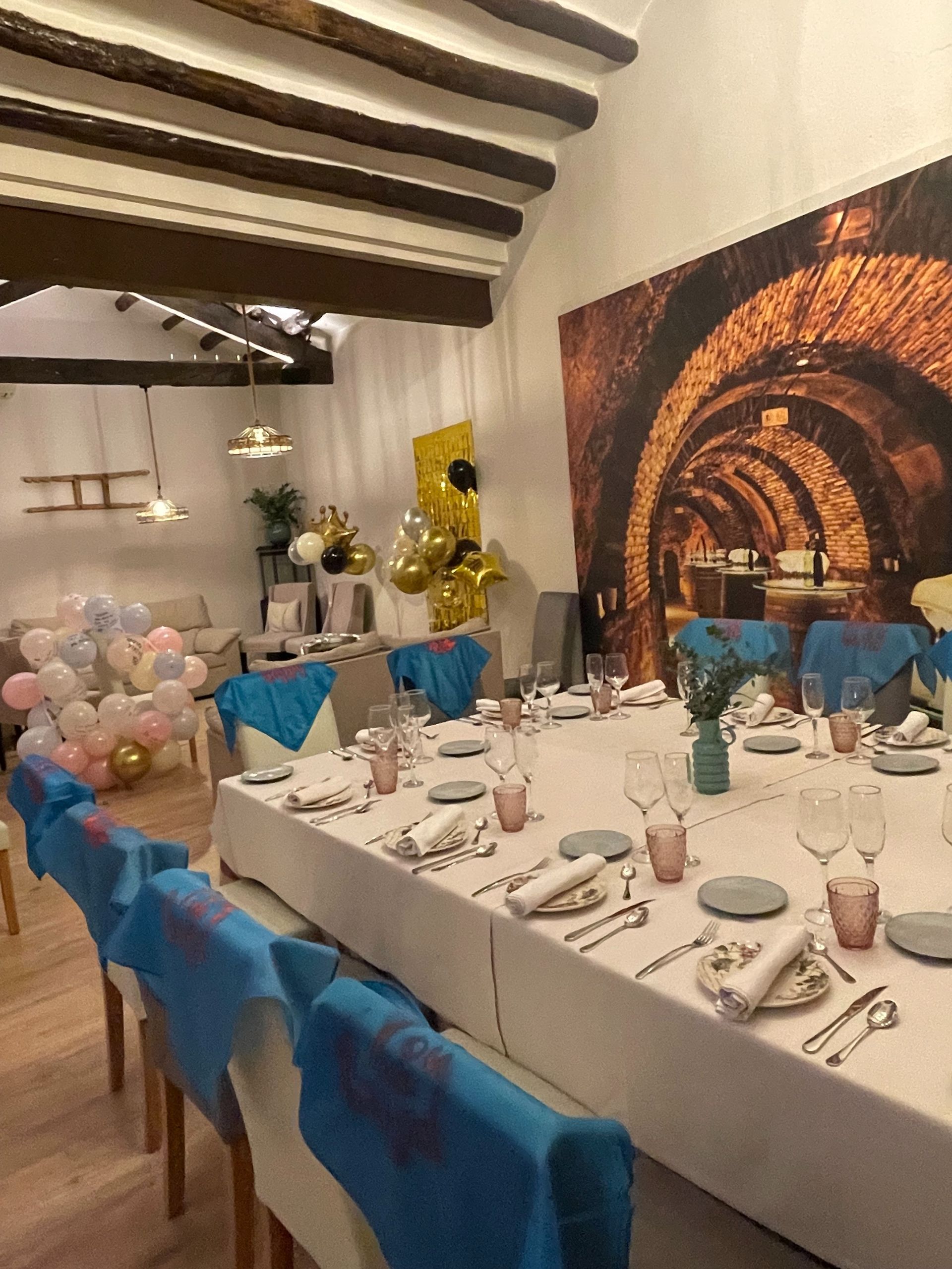 Una mesa larga con platos, vasos y globos encima.