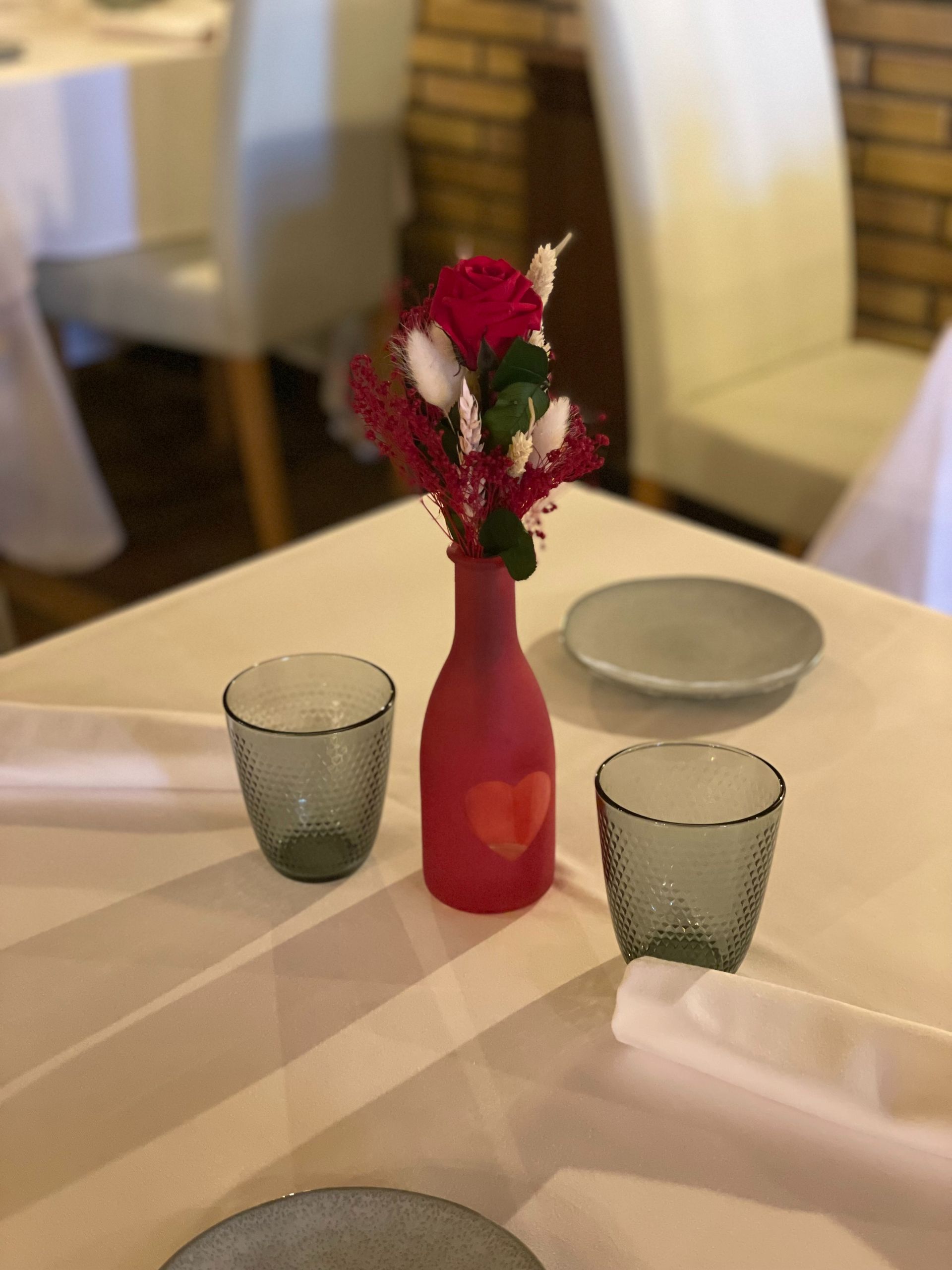 Una mesa con dos vasos y un jarrón con flores.