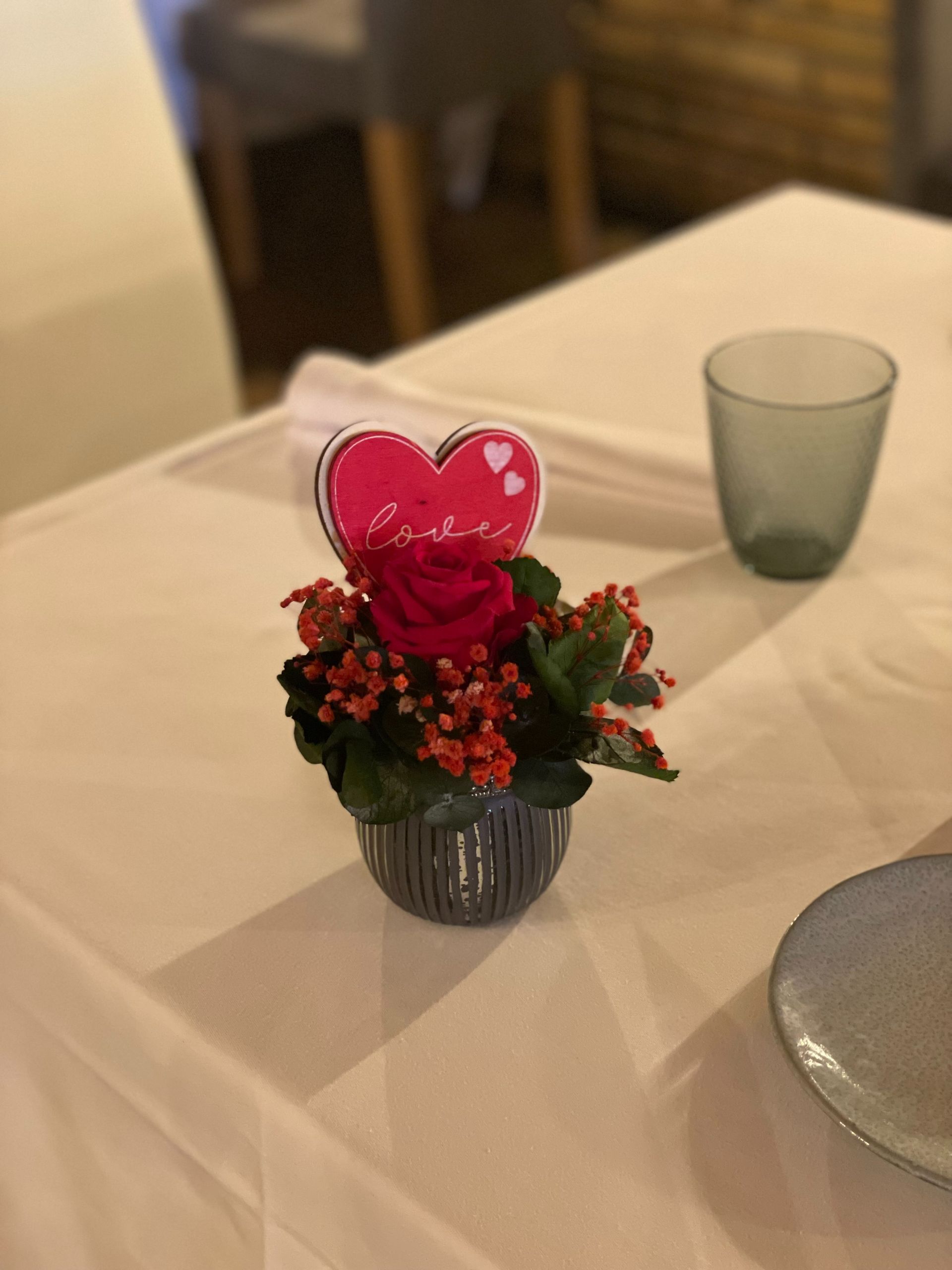 Un pequeño jarrón con flores y un corazón encima.