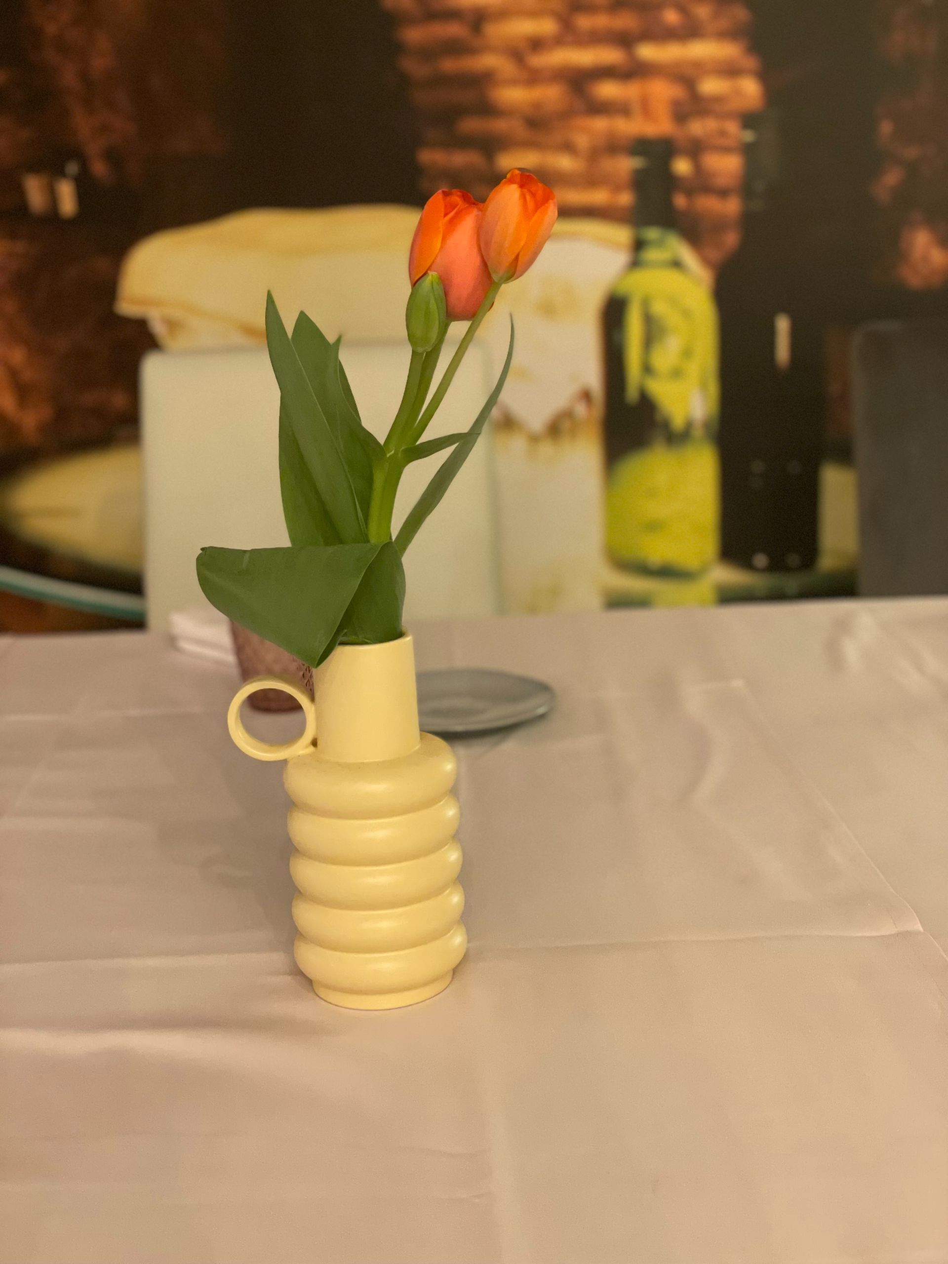 Un jarrón amarillo con flores sobre una mesa.