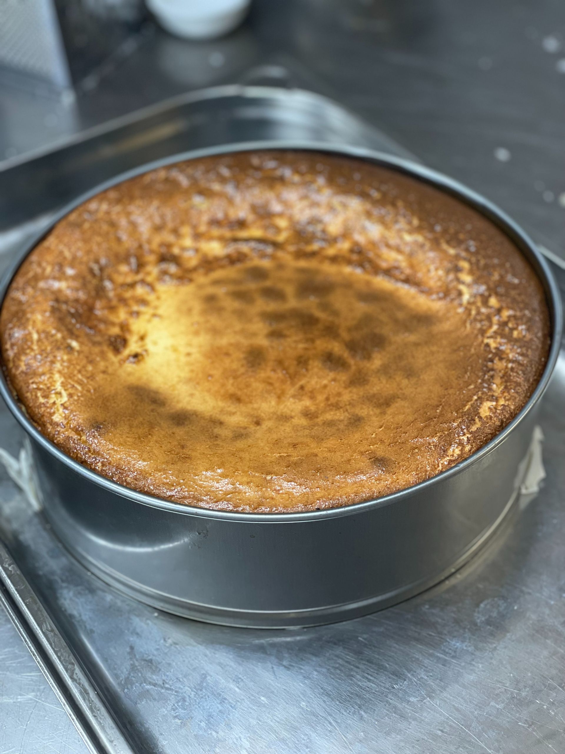 Una tarta de queso reposa sobre una bandeja de metal sobre un mostrador.