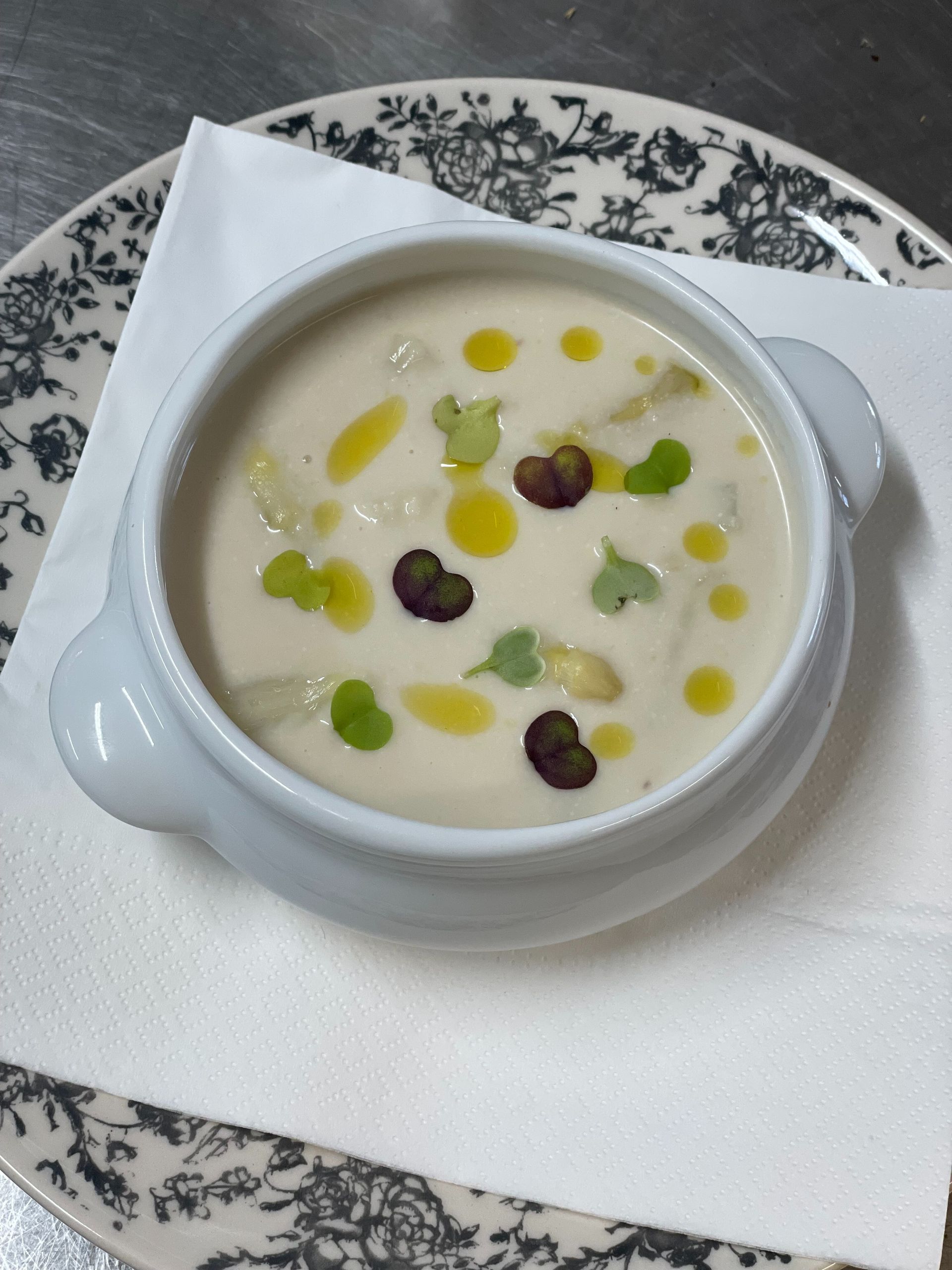 Un tazón de sopa en un plato con una servilleta