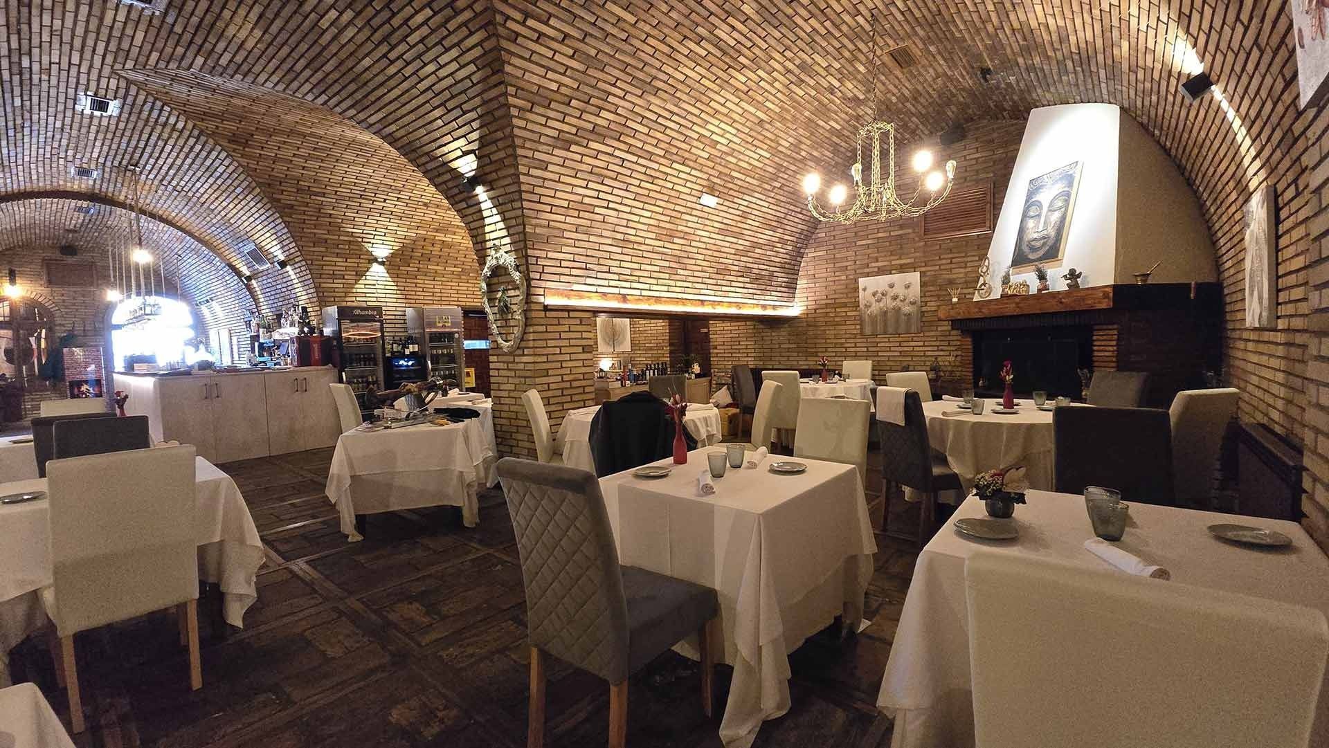 Un restaurante con mesas y sillas y un techo de ladrillo.